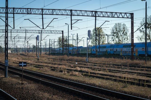 Railroad sidings with a chain of old, decommissioned and deteriorating rolling stock of Polregio

Old double-decker Bmnopux cars stand out

Lots and lots of tracks and overhead railway powerlines are visible