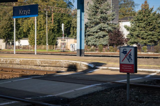 A crossing on train tracks in the middle of the platform right next to the station building, but there's a sign prohibiting passengers from crossing