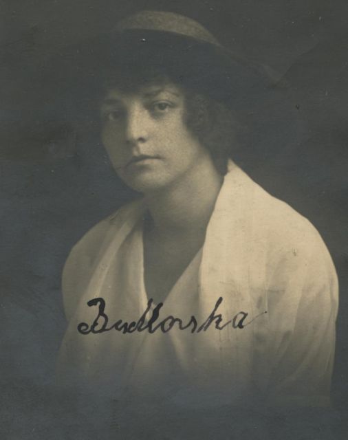 Vintage black and white portrait of a woman wearing a hat and a light-colored shirt, with the name inscribed at the bottom.