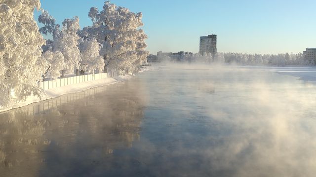 Auringossa pakkasessa höyryävä Oulujoki