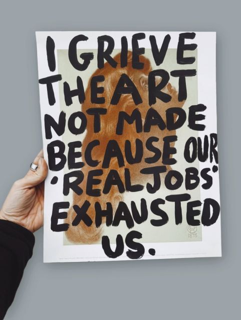 A hand holding a sign saying: I grieve the art not made because our "Real jobs" exhausted us.