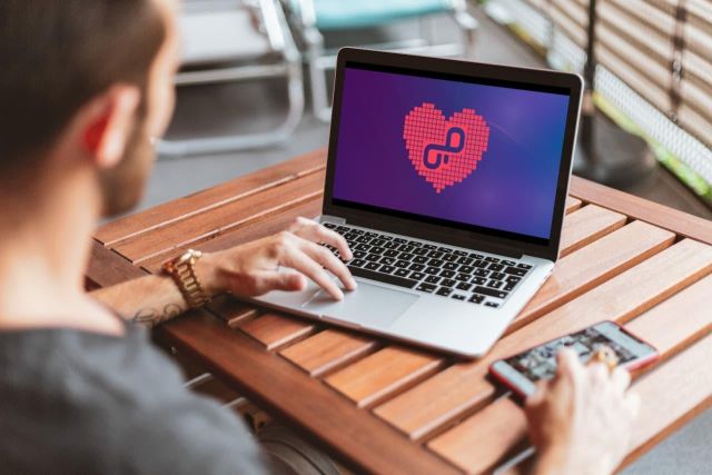 A person working on their laptop, OpenProject logo shown in a heart.