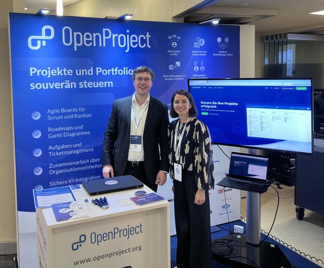 Robin Wagner and Felicia Mundhenke at the OpenProject booth during the Zukunftskongress Staat & Verwaltung 2026 in Berlin. They are presenting OpenProject's open source project and portfolio management platform and engaging with public sector attendees.