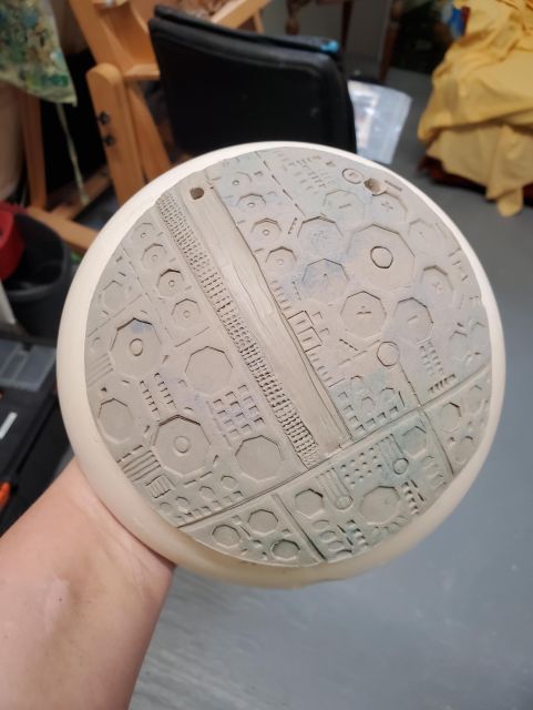 A space rock of a tech planet or perhaps the outside of a dyspn sphere. There are numerous sizes of geometric shapes and lines creating a fabricated surface.