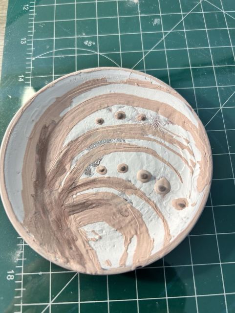 Small plate with layers of glazes applied on top of each other in an abstractish pattern of swooshes and dots. 