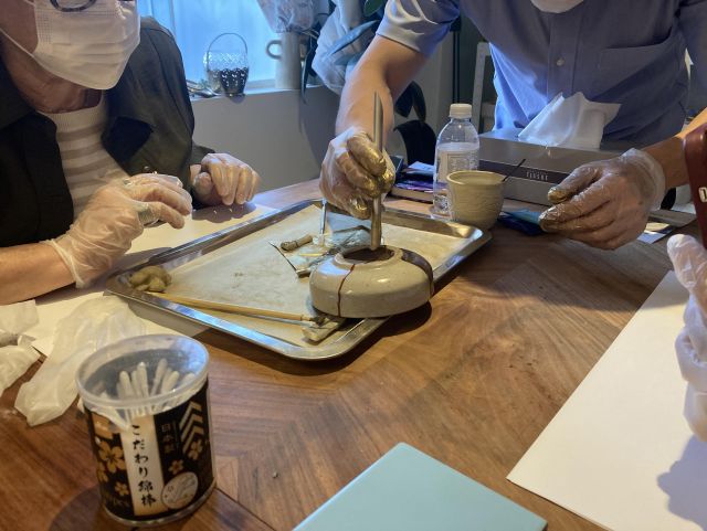 Photo of a two people around a table with a tray containing a bowl and other utensils all covered in golden powder.